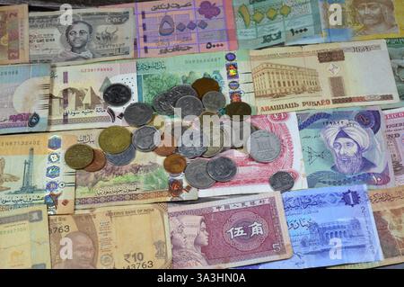 Münzen aus verschiedenen Ländern und Europa auf verschiedenen Banknoten aus verschiedenen Ländern wie irakische Dinar, libyscher Dinar, sudanesische Pfund, indische Rupie Stockfoto