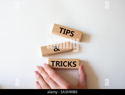 Symbol für Tipps und Tricks. Holzblöcke mit Worten Tipps und Tricks. Schöner weißer Hintergrund. Geschäftsmann Hand. Geschäftskonzept und Tipps und Tricks. Stockfoto