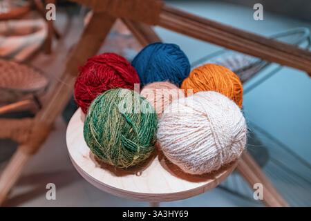 Bunte Garnkugeln sitzen auf einem kleinen Holztisch, bereit für ein Strickprojekt Stockfoto