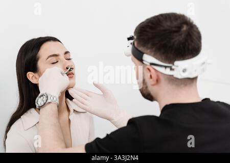 Der HNO-Arzt untersucht die Mädchennase vor der Endoskopie der Nase. Beratung mit dem HNO-Arzt. Rhinoskopie der weiblichen Nase Stockfoto
