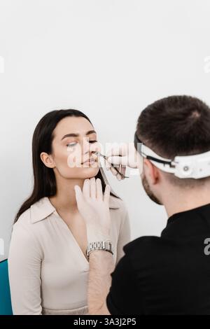 Der HNO-Arzt untersucht die Mädchennase vor der Endoskopie der Nase. Beratung mit dem HNO-Arzt. Rhinoskopie der weiblichen Nase Stockfoto