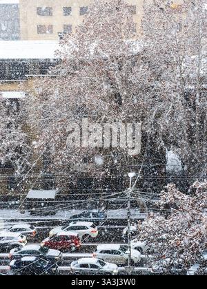 Blick über die Autos auf der Straße bei Schneefall auf der Mashtots Avenue am Winterabend in Jerewan Stadt, Armenien Stockfoto