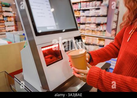 Frau, die Lebensmittel an einem Selbstbedienungsautomat in einem Lebensmittelgeschäft scannt, genießt den Komfort moderner Einzelhandelstechnologie Stockfoto