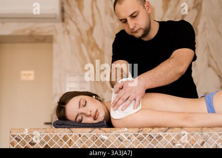 Entspannung im Wellnesscenter. Der Masseur macht eine Massage. Türkischer Schaum Massage und Peeling mit Kese Handschuh Stockfoto