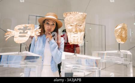 17. Januar 2025, Louvre Abu Dhabi, Vereinigte Arabische Emirate: Tourist Holding Kinn, nachdenklich Blick auf präkolumbianische Goldgegenstände, die in einem Museum ausgestellt wurden Stockfoto