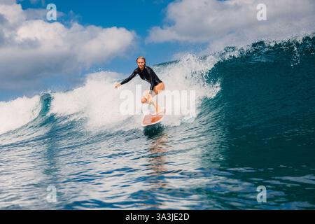 Wunderschönes Surfermädchen auf dem Surfbrett. Frau im Meer beim Surfen. Surfer und Barrel Wave Stockfoto