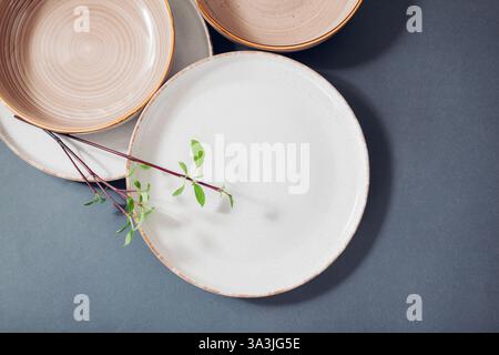 Nahaufnahme von glasierten keramischen Küchenartikeln auf grauem Hintergrund. Set mit weißen Beige-Dinner- und Suppenteller Stockfoto