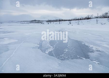 Gefrorener See Tornetrask. Bewölkter Wintertag. Berge im Hintergrund. Abisko, Lappland, Schweden. Stockfoto