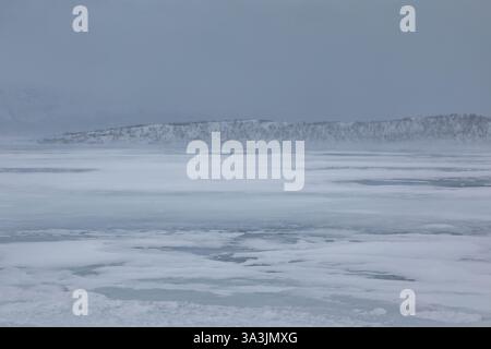 Gefrorener See Tornetrask. Bewölkter Wintertag. Berge im Hintergrund. Abisko, Lappland, Schweden. Stockfoto