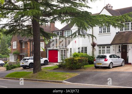 London, Großbritannien - 18. Mai 2024. Reihe von Doppelhaushälften mit Autos, die auf der Einfahrt in einem Naturschutzgebiet eines Londoner Vorortes geparkt sind. Pinner, London, Großbritannien Stockfoto