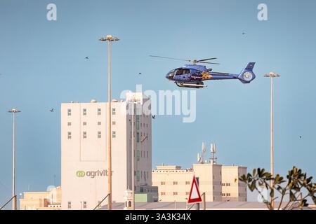 18. Januar 2025, Abu Dhabi, VAE: Blauer Hubschrauber fliegt über Industriegebäude Stockfoto