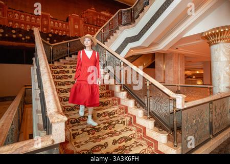 19. Januar 2025, Emirates Palace Hotel, Abu Dhabi, Vereinigte Arabische Emirate: Elegante Frau, die die Treppe einer luxuriösen Hotellobby hinabsteigt, zeigt Opulenz und Reisen Stockfoto