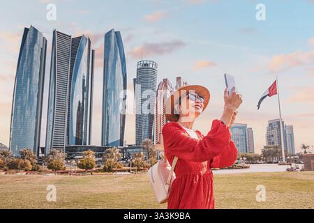 Asiatische Frau, die an einem sonnigen Tag ein Foto in Abu Dhabi mit ihrem Smartphone macht Stockfoto