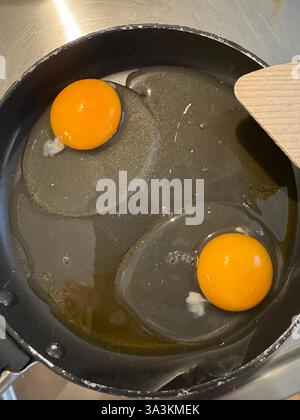 Zwei rohe Eier in einer kleinen Pfanne mit beidseitigem Spachtel Stockfoto