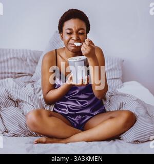Zerfall Konzept. Weinendes Mädchen, das Eis im Bett isst Stockfoto