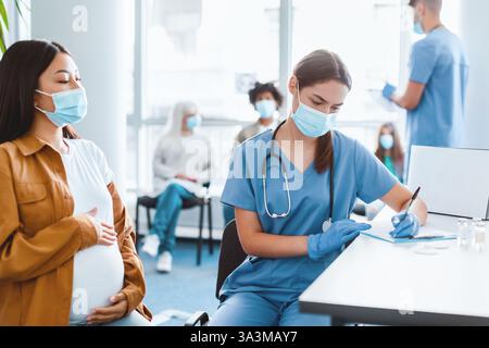 Impftermin in einer Klinik mit einer betreuten schwangeren Frau Stockfoto