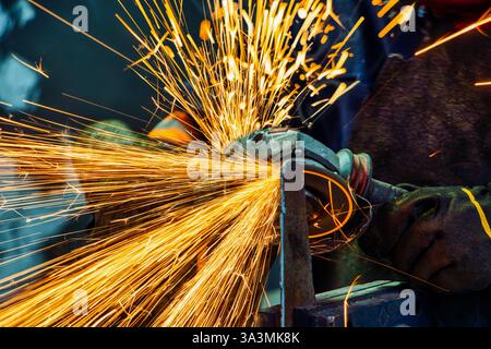 Winkelschleifer, Handwerker mit Elektrowerkzeugen, die Metall in einer Fabrik schleifen Stockfoto