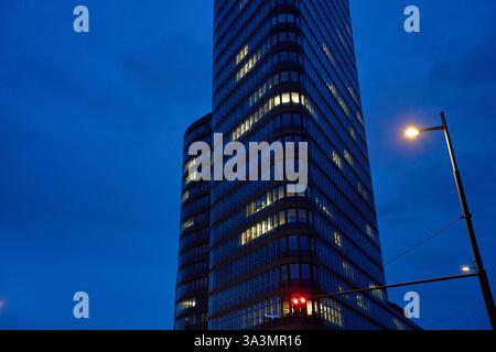 Moderner Glashochhaus mit beleuchteten Bürofenstern vor dem Nachthimmel. Bürohochhaus mit leuchtenden Lichtern im nächtlichen Stadtbild Stockfoto