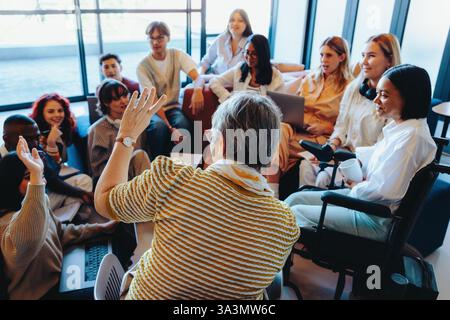 Eine vielfältige Gruppe von Hochschulabsolventen führt ein lebhaftes Gespräch mit Freunden und hebt die Zusammenarbeit und Teamarbeit in einem modernen Bildungsbereich hervor Stockfoto