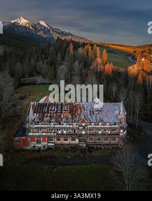 Zdiar, Slovakia - Aerial view of an abandoned wooden house in the High Tatras region of Slovakia at winter time with dramatic colorful sunrise sky Stockfoto