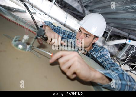 Elektriker Arbeiter, der Deckenlampe installiert Stockfoto