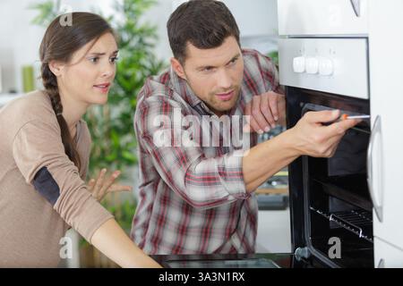 Frau und Mann überprüfen einen Ofen Stockfoto