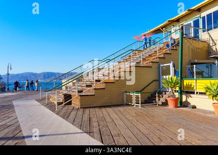 Santa Monica, Kalifornien - 16. Januar 2025: Helle und einladende Treppe, die zu einem lebhaften Gebäude am Santa Monica Pier führt, eingerahmt vom Pacifi Stockfoto