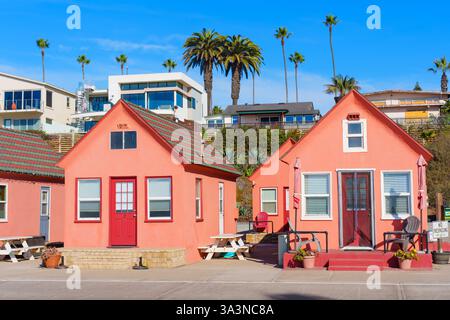Oceanside, Kalifornien - 27. Dezember 2024: Reihe von leuchtend rosa Cottages in Strandnähe in Oceanside, Kalifornien, mit Palmen und en Stockfoto