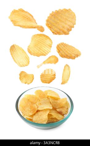 Leckere Kartoffelchips fallen in Schüssel auf weißem Hintergrund Stockfoto