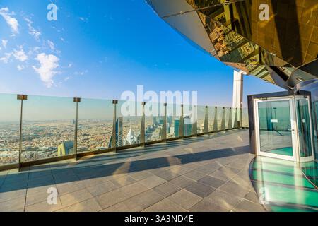 Die Dachterrasse bietet einen atemberaubenden Panoramablick auf die Skyline von Riad und verfügt über moderne Architektur, Glasgeländer und reflektierende Oberflächen unter einem klaren Himmel Stockfoto