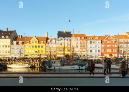 Kopenhagen, Dänemark - 17. März 2024 : malerischer Blick auf das farbenfrohe Hausgebäude entlang des Kanals mit Booten und Touristen, die im Hafen von Nyhavn unterwegs sind Stockfoto