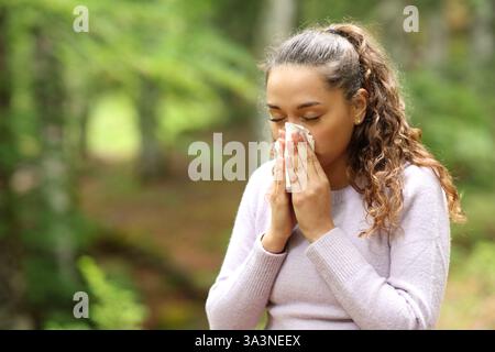Kranke Frau, die die Nase bläst, während Gewebe in der Natur laufen Stockfoto