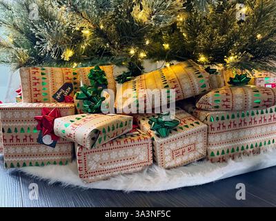Weihnachtsgeschenke in festliches Papier unter einem beleuchteten Baum Stockfoto