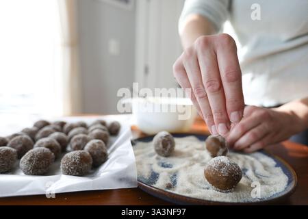 Nahaufnahme von Hand, die Rohzucker auf Keksteig streuselt Stockfoto