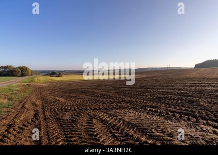 Spuren von Automobilrädern auf dem gepflügten Boden des Feldes, Spuren von Traktoren und anderen landwirtschaftlichen Maschinen auf dem Boden auf dem Feld Stockfoto