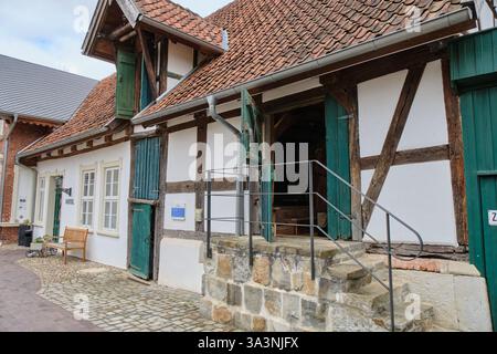 16. März 2025: Neubruchhaussen: Traditionelle Fachwerkwassermühle mit grünen Holztüren, rotem Ziegeldach und Steintreppe nach innen. Stockfoto