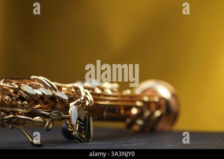 Jazz. Ein schönes Saxophon auf schwarzem Tisch vor farbigem Hintergrund, Nahaufnahme Stockfoto