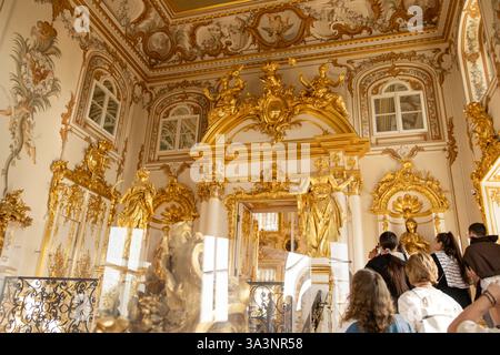 17. September 2024, St. Petersburg, Russland. Besucher erkunden den luxuriösen goldenen Saal des Großen Peterhofs, umgeben von kompliziertem Barock Stockfoto