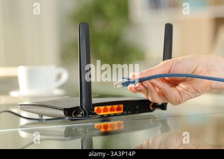 Nahaufnahme einer Frau, die ein ethernet-Kabel hält, um das Modem anzuschließen Stockfoto
