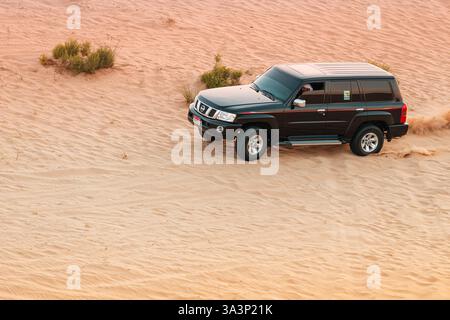 20. Januar 2025, Abu Dhabi, VAE: Geländefahrzeug, das durch weite Wüstensanddünen navigiert und Wolken aus Staub und Sand aufwirft Stockfoto