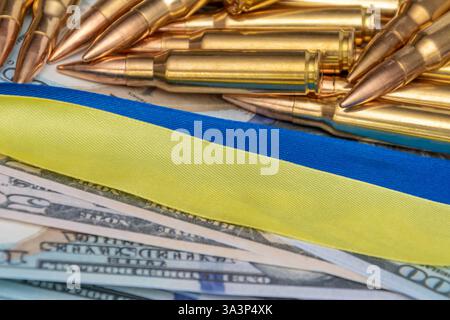 Militärmunition - Patronen auf dem Hintergrund der ukrainischen Flagge und Dollar. Stockfoto