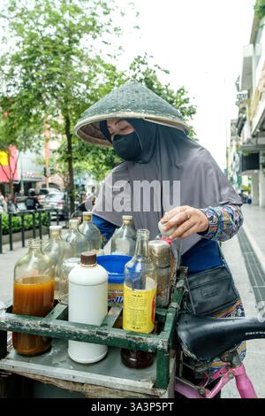 Straßenverkäufer mit Maske und traditionellem Hut in yogyakarta, indonesien Stockfoto