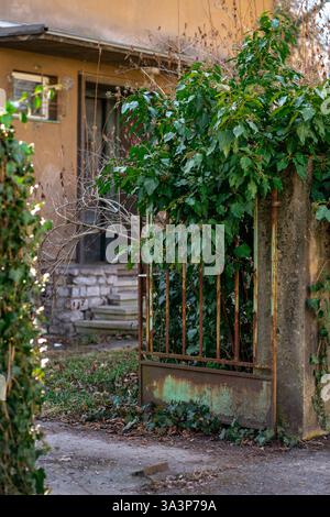 Blick auf das verlassene Territorium eines Privathauses mit einem alten rostigen Tor Stockfoto