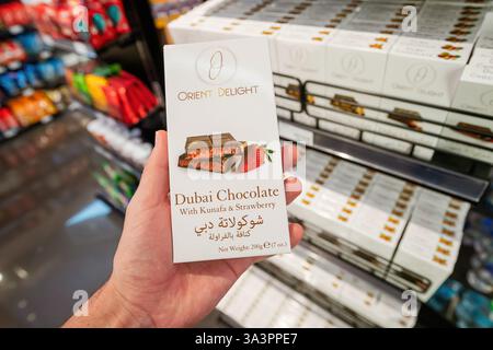 23. Januar 2025, Abu Dhabi, VAE: Hand in einem Duty-Free-Supermarkt mit einem Schokoladenriegel aus Dubai mit Kunafa- und Erdbeergeschmack Stockfoto