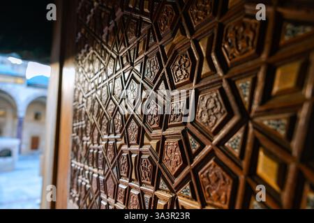Islamisches geometrisches Muster an der Holztür einer Moschee im Fokus. Islamisches Hintergrundfoto. Stockfoto