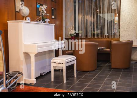 Gemütliches Interieur mit weißem Klavier und Ledersitzbereich Stockfoto