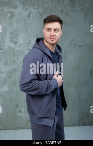 Ein Mann, der einen Bart trägt, trägt einen bequemen grauen Hoodie, der einen trendigen Stil zeigt, der moderne Modeentscheidungen widerspiegelt Stockfoto