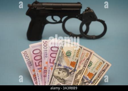 Euro- und Dollarscheine mit Pistole auf dem Tisch. Stockfoto