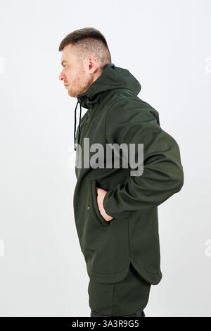 Ein Mann mit einer leuchtend grünen Jacke hat beide Hände bequem in den Jackentaschen verstaut Stockfoto