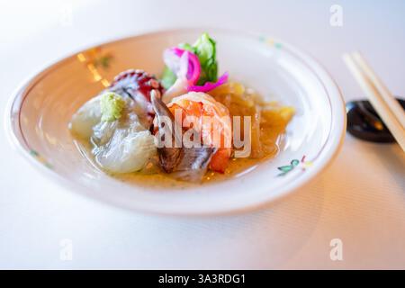 Japanische Vorspeise mit frischen Garnelen, Weichtieren und fermentiertem Gemüse, serviert in einem traditionellen Keramikgericht mit Wasabi-Beilage und pi Stockfoto